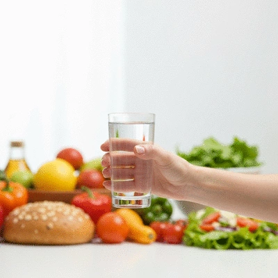 Close-up of a person's hand holding a clear glass of water, with a blurred background of healthy food items, emphasizing hydration and nutrition for recovery, no text, no words, no typography, no labels, clean image